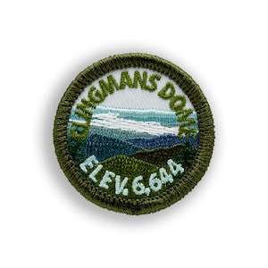 May include: Embroidered patch featuring a mountain landscape with the text "Clingmans Dome" and "Elev. 6,644". The patch has a green border and depicts a scenic view with blue and green hues.