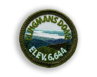 May include: Embroidered patch featuring a mountain landscape with the text "Clingmans Dome" and "Elev. 6,644". The patch has a green border and depicts a scenic view with blue and green hues.