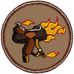 May include: A brown leather saddle with flames coming out of the side. The saddle is on a tan background with a brown border.