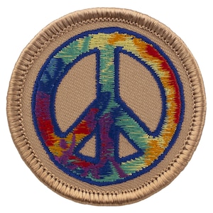 May include: A round, tan fabric patch with a blue peace sign embroidered in the center. The peace sign is filled with a colorful tie-dye pattern.