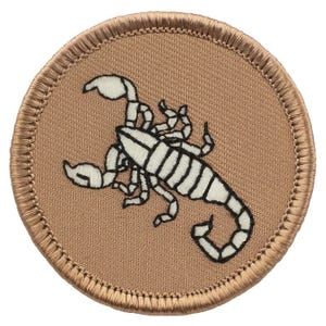 May include: A brown embroidered patch with a white scorpion design. The scorpion is facing right and has a curled tail.
