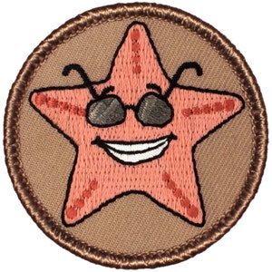 May include: A brown embroidered patch with a pink starfish wearing sunglasses and smiling. The starfish has a white smile and white eyes.