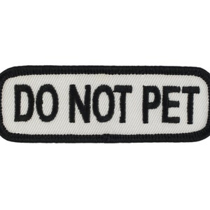 May include: White rectangular patch with black border and black embroidered text that reads "DO NOT PET".