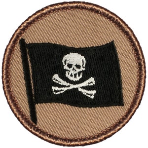 May include: A round, brown embroidered patch with a black pirate flag featuring a white skull and crossbones.