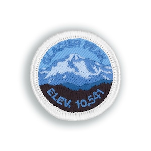 May include: A blue and white embroidered patch with a mountain scene and the text "Glacier Peak" and "Elev. 10,541".