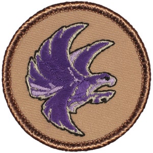 May include: Purple embroidered patch with a stylized bird design on a tan background with a brown border.