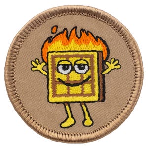 May include: Embroidered patch featuring a smiling waffle character with flames atop its head. The waffle is yellow and brown, with arms and legs, set against a tan background with a stitched border. A fun, whimsical design.