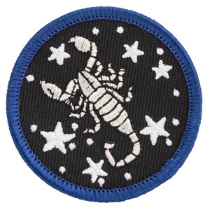May include: A black embroidered patch with a white scorpion and white stars on a black background. The patch has a blue border.