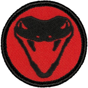 May include: Round embroidered patch featuring a black snake head design on a red background. The snake head is centered within the red circle, and the patch has a black border. The patch is likely for clothing or accessories.