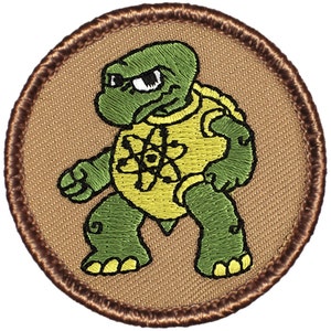 May include: A brown embroidered patch with a green turtle wearing a yellow shirt with an atom symbol. The turtle has a grumpy expression.
