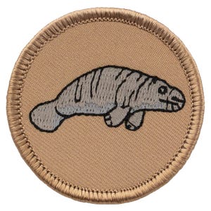 May include: A beige embroidered patch with a gray manatee on a tan background.