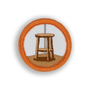 May include: Orange and brown embroidered patch with a wooden stool in the center.