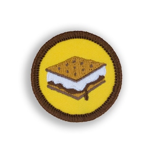 May include: A brown and yellow embroidered patch with a s'more on it. The s'more is made of a graham cracker, marshmallow, and chocolate.