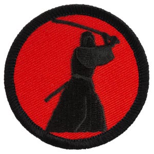 May include: A black embroidered patch with a red background. The patch depicts a silhouette of a person holding a sword in a fighting stance.