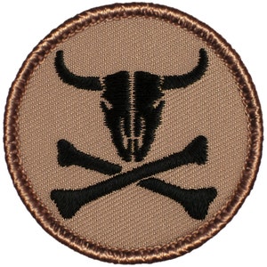 May include: A round, tan embroidered patch with a black bull skull and crossbones design.
