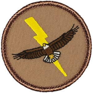 May include: A brown embroidered patch with a yellow lightning bolt and a brown eagle flying through it. The patch has a brown stitched border.