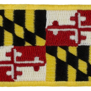 May include: A yellow, black, red, and white embroidered patch featuring the Maryland state flag.