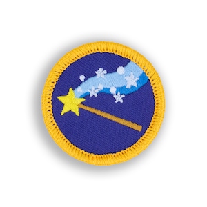 May include: A blue and yellow embroidered patch with a star-shaped wand and a trail of snowflakes. The patch is surrounded by a yellow border.