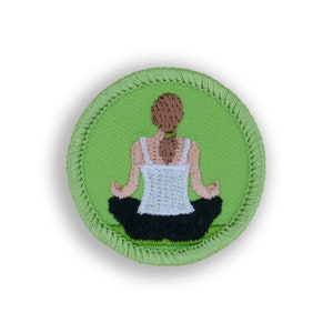 May include: A green embroidered patch with a woman sitting in a yoga pose on a green mat. The woman is wearing a white tank top and black pants.