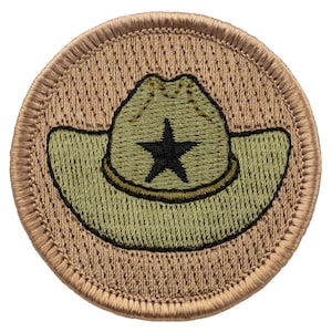 May include: A tan embroidered patch with a green cowboy hat with a black star on the front.