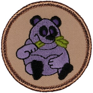 May include: Embroidered patch featuring a purple panda bear with black accents, holding a green object in its mouth. The panda is centered on a tan background, framed by a brown stitched border. A whimsical design.