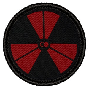 May include: Black and red embroidered patch with a stylized radiation symbol. The symbol is red with a black center and three circles.