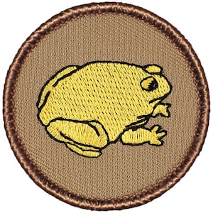 May include: A brown embroidered patch with a yellow frog on a tan background. The frog is facing the right side of the patch.