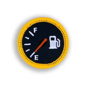 May include: A yellow and black embroidered patch with a gas gauge showing a low fuel level. The gauge is labeled "F" for full and "E" for empty. A gas pump icon is also included.
