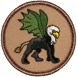 May include: A brown embroidered patch with a black and white griffin with green wings. The griffin is standing on a tan background.