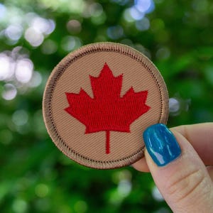 May include: A brown fabric patch with a red embroidered Canadian maple leaf.