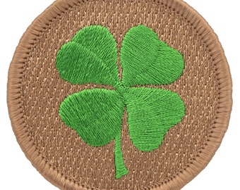 May include: A round, brown patch with a green embroidered four-leaf clover.