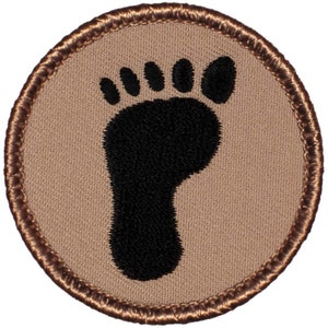 May include: A brown embroidered patch with a black footprint in the center.