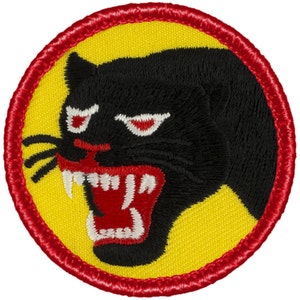 May include: A yellow and red embroidered patch with a black panther head with a red open mouth and white teeth. The panther has red eyes and white markings around the eyes.