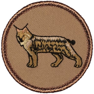 May include: A brown embroidered patch with a brown outline, featuring a brown and black lynx.