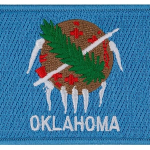 May include: Embroidered patch featuring the state flag of Oklahoma. The patch is blue with a brown circle in the center. The circle contains a green, leafy branch and a white arrow. The word "OKLAHOMA" is embroidered in white below the circle.