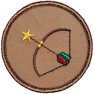 May include: A circular patch with a brown background and a stitched brown border. The patch features a bow and arrow design with a yellow star and arrow fletching in red and green. The patch is likely for a scout or similar organization.