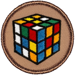 May include: A brown embroidered patch with a colorful Rubik's Cube design.