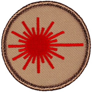 May include: A brown embroidered patch with a red laser beam design. The patch is circular and has a brown border.