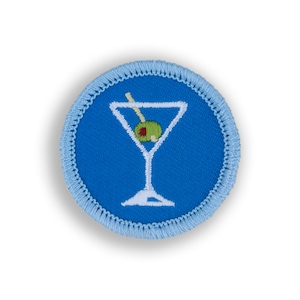 May include: A blue and white embroidered patch with a martini glass and olive. The patch is circular and has a light blue border.