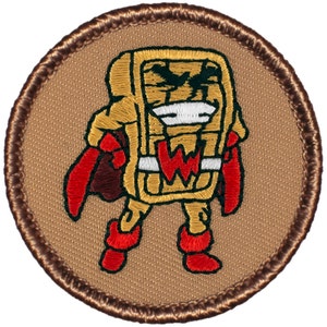 May include: A brown embroidered patch with a cartoon character wearing a red cape and a white "W" on its chest. The character is shaped like a waffle and has a brown and yellow color scheme.