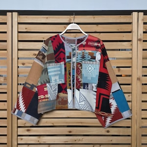 May include: A patchwork jacket with a variety of patterns and colors, including red, blue, tan, and black. The jacket is hanging on a wooden hanger against a wooden background. The jacket has a unique, handcrafted appearance.