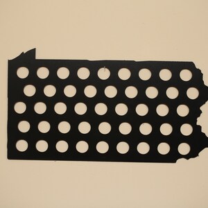 Peut inclure: Contour de l'&eacute;tat de Pennsylvanie en m&eacute;tal noir avec 42 trous ronds pour les capsules de bouteilles.