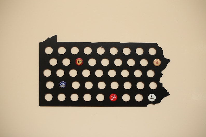 Peut inclure: Contour en m&eacute;tal noir de l'&eacute;tat de Pennsylvanie avec 49 d&eacute;coupes circulaires pour des capsules de bouteilles. Certaines des d&eacute;coupes sont remplies de capsules de bouteilles avec diff&eacute;rents logos et couleurs.