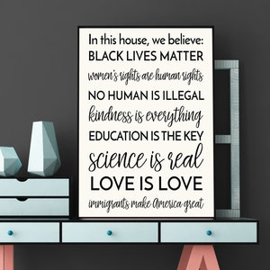 May include: Black and white print with the text "In this house, we believe: BLACK LIVES MATTER, women's rights are human rights, NO HUMAN IS ILLEGAL, kindness is everything, EDUCATION IS THE KEY, science is real, LOVE IS LOVE, immigrants make America great."