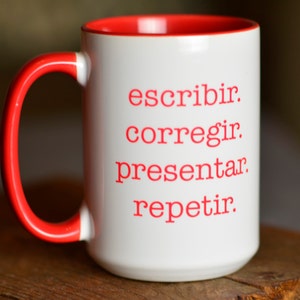 May include: White ceramic mug with a red rim and handle. The mug has the words "escribir, corregir, presentar, repetir" printed in red on the front.