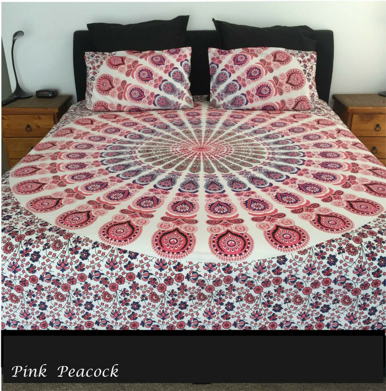 Peut inclure: Une housse de couette blanche, rose et bleue &agrave; motif mandala avec une bordure florale. La housse de couette est sur un lit avec une t&ecirc;te de lit et des oreillers noirs.