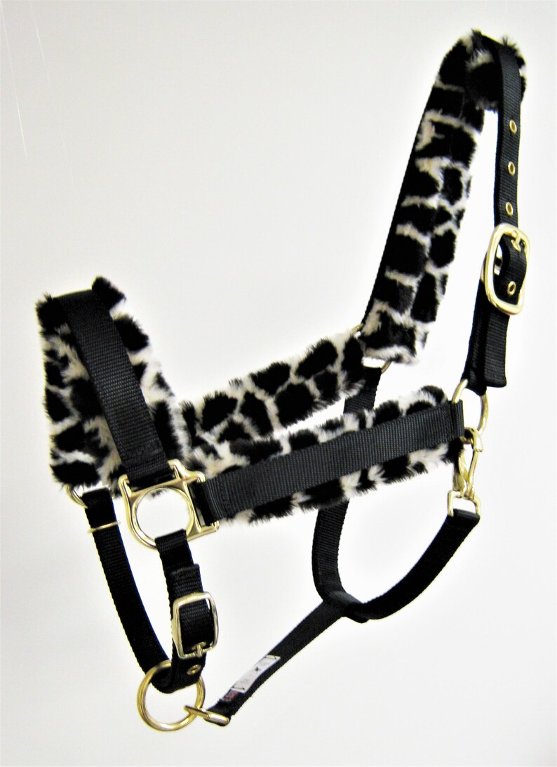 May include: Black nylon horse halter with a white and black leopard print fleece lining. The halter has gold metal hardware.