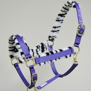 May include: Purple horse halter with a zebra print fleece lining. The halter has a brass buckle and rings.