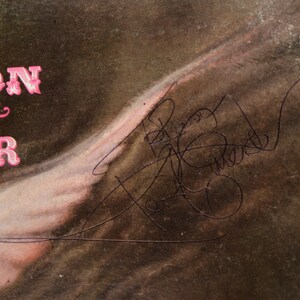 May include: Vintage album cover with the text "SON & HER" in pink, stylized lettering. The cover features a faded, sepia-toned image with a signature in black ink. The overall aesthetic suggests a retro music theme.