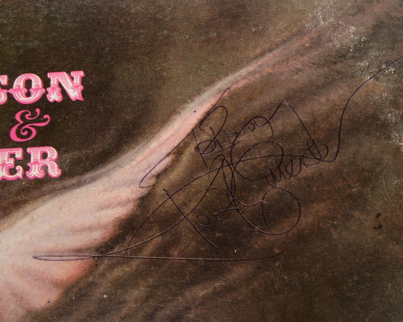 May include: Vintage album cover with the text "SON & HER" in pink, stylized lettering. The cover features a faded, sepia-toned image with a signature in black ink. The overall aesthetic suggests a retro music theme.